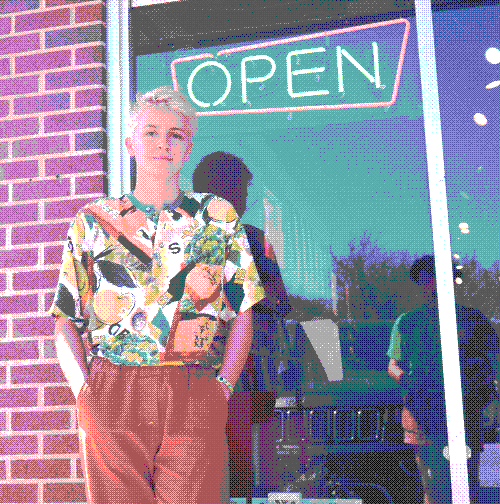 Izzy standing in front of an Open sign